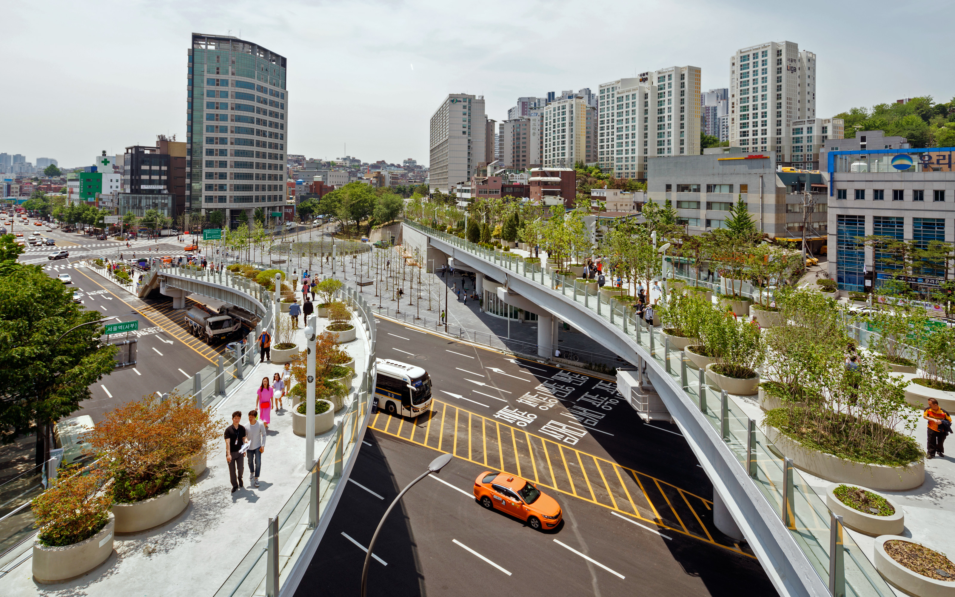 The former Seoul highpass was transformed into an approx. 1 km long Skygarden, situated 17 m above street level. People strolling on a large roof garden in the city